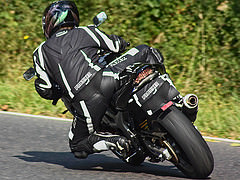 Obraz motocyklisty na wyścigach, który kolanem już prawie dotyka asfaltu.
